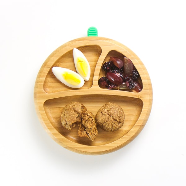 baby-led weaning breakfast on wooden plate with 3 sections - mini muffins, cut hard boiled egg, grapes and blackberries