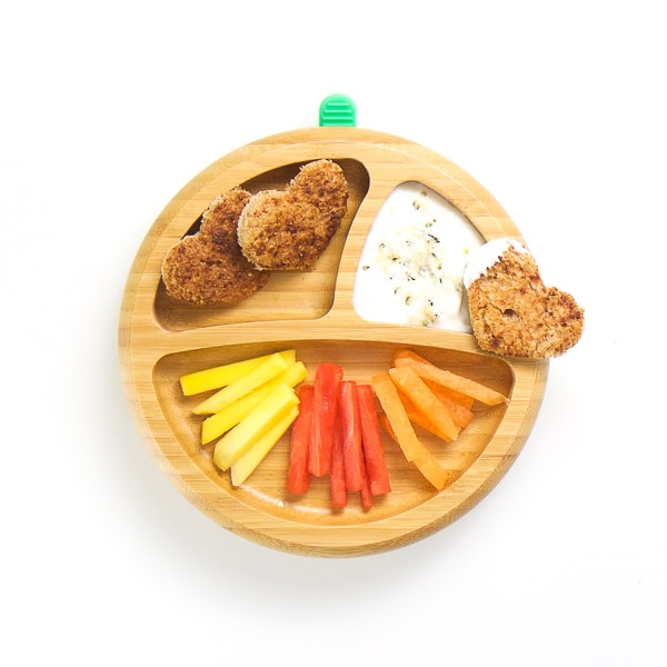 finger food breakfast on wooden plate with 3 sections - strips of mango, watermelon and cantaloupe with heart shaped cinnamon toast, yogurt with coconut and hemp seeds for dipping