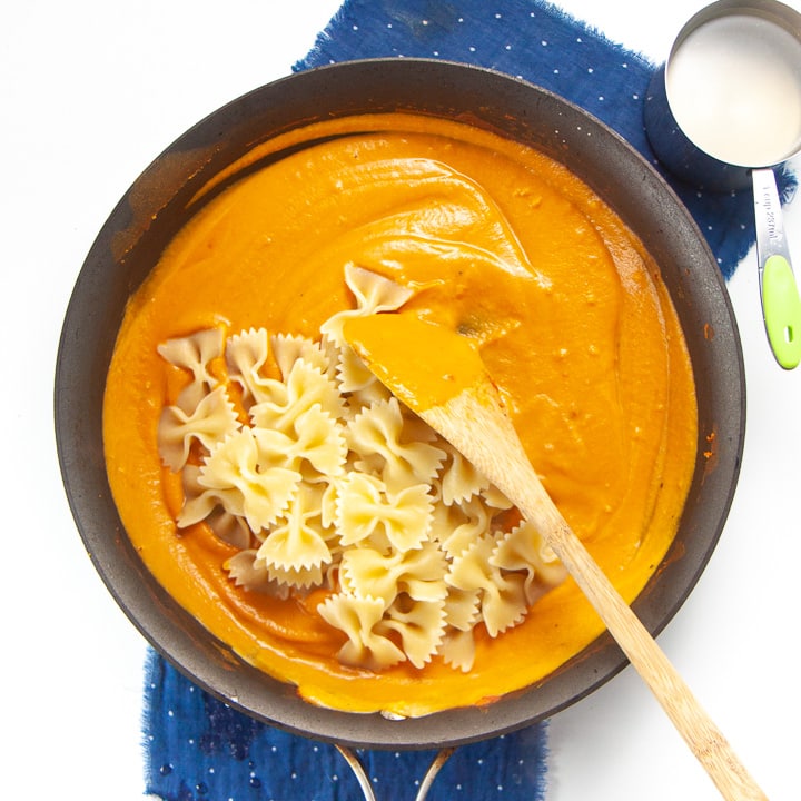 pumpkin pasta sauce with cooked pasta in a skillet.