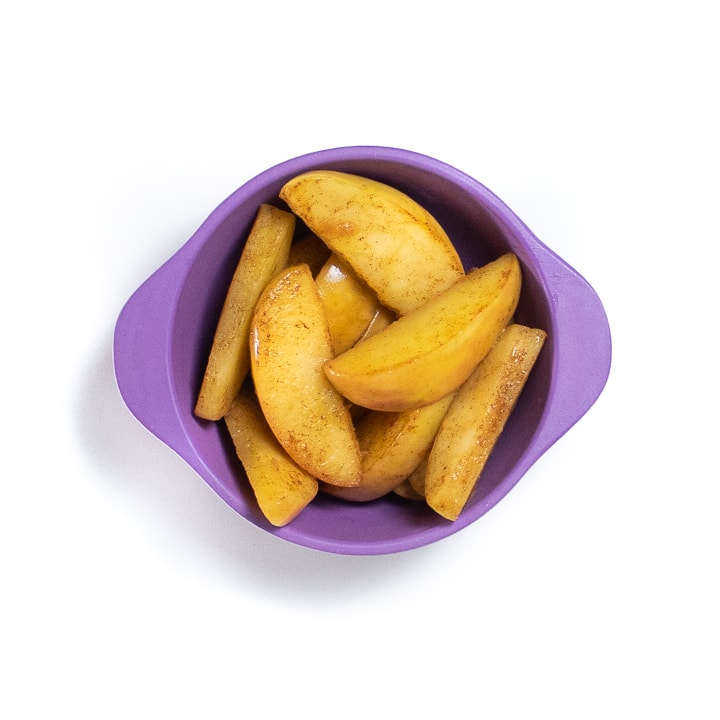 Small purple bowl with sautéed apple slices for baby.