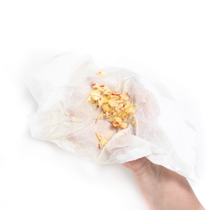 hand holding a paper towel with grated apple for baby.