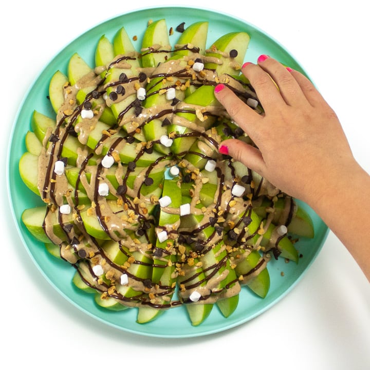 Small kids hand reaching for an apple slice.