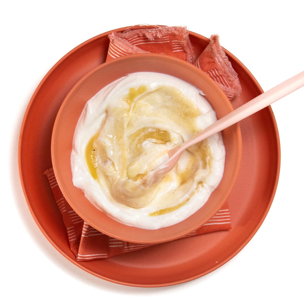 A pink kids bowl and plate full with apple yogurt.