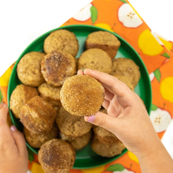 Hand holding up a mini applesauce muffin made with wholesome ingredients.