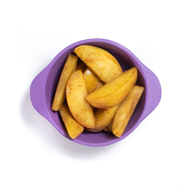 Purple small baby bowl filled with soft apples for baby. 