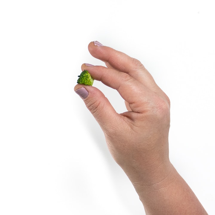 handing using a pincer grasp to pick up a piece of broccoli.