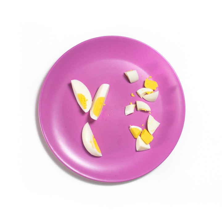 Pink baby plate with sliced and chopped hard boiled eggs.