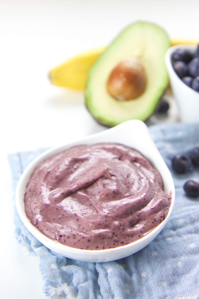 Small white bowl filled with blueberry banana avocado baby food puree.