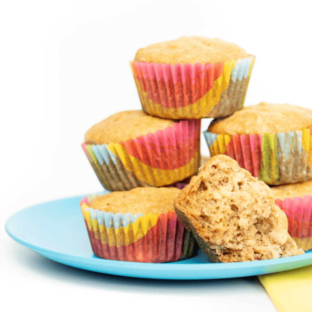 blue kids plate on a white countertop with colorful muffin liners with soft and moist banana muffins. 