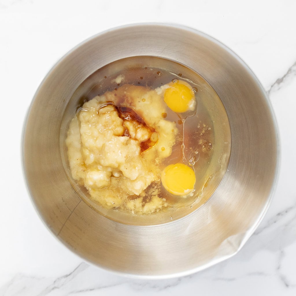 Silver mixing bowl, with muffin ingredients on a marble countertop.