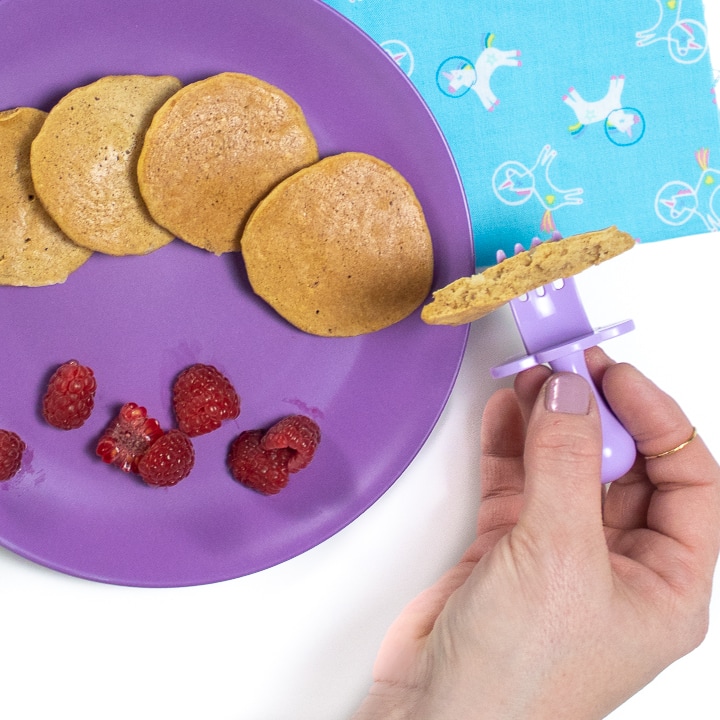 Hand holding a piece of banana pancakes for baby or toddler.