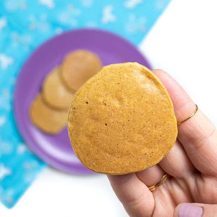 Hand holding a fluffy banana pancake for baby.