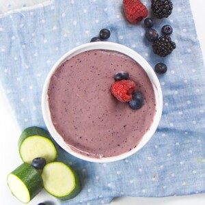 Bowl of purple baby breakfast cereal surrounded by produce.