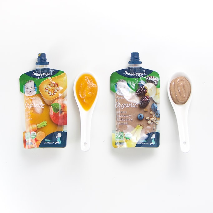 2 organic happy baby baby food pouches with spoons next the them with puree inside.