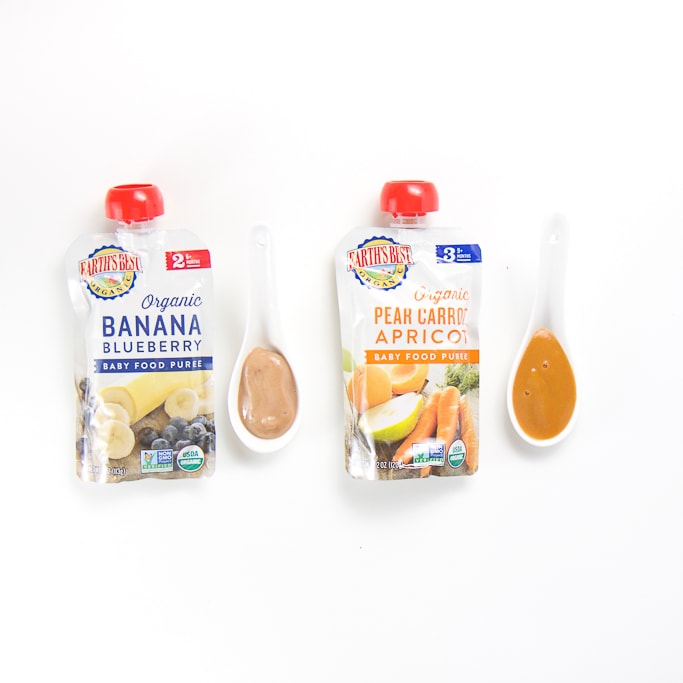 2 organic earths best baby food pouches with spoons next the them with puree inside.