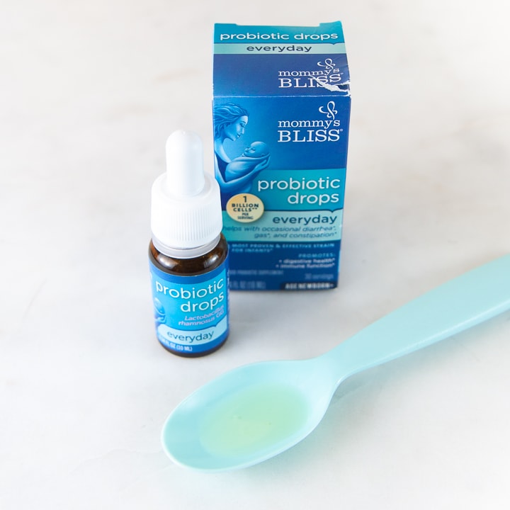 Box of probiotics and spoon of liquid probiotics in a spoon.