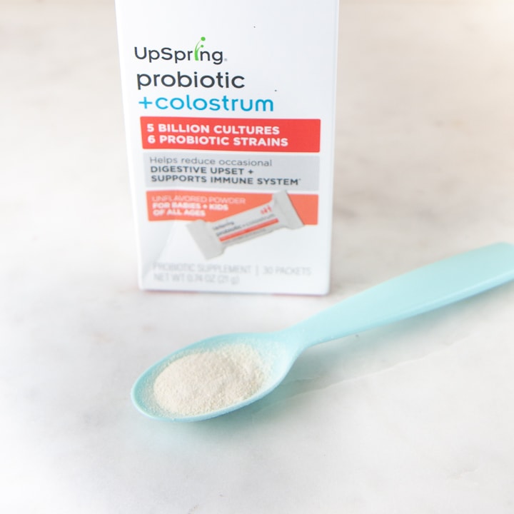 A Box of probiotics with a spoon full of powder probiotics