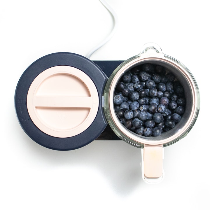 BEABA babycook with blueberries inside of the stainless steel container.