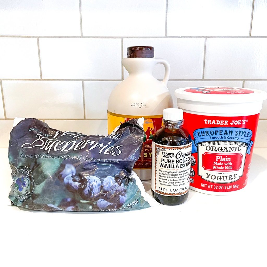 A white kitchen with the spread of ingredients for blueberry yogurt.