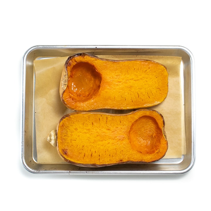 Roasted butternut squash laying on a baking sheet.