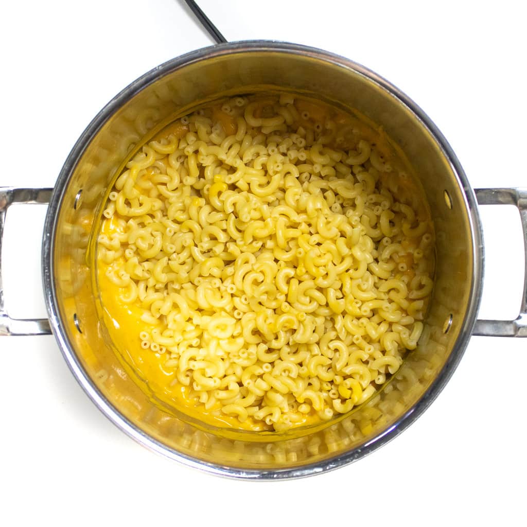 The largest silver stock pot full of butternut squash purée and cooked macaroni.