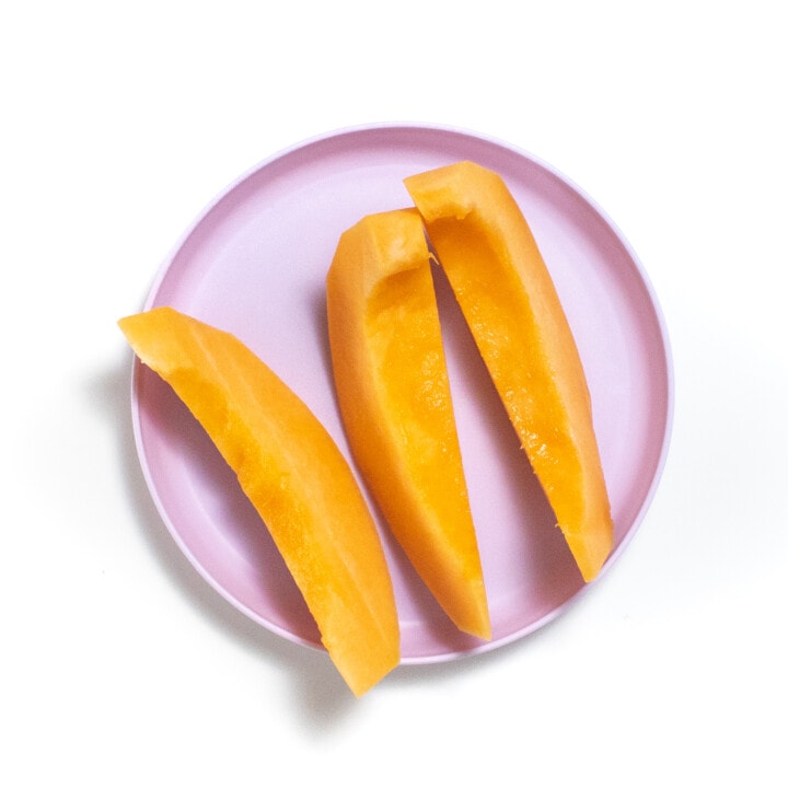 A purple kids play with wedges of cantaloupe.