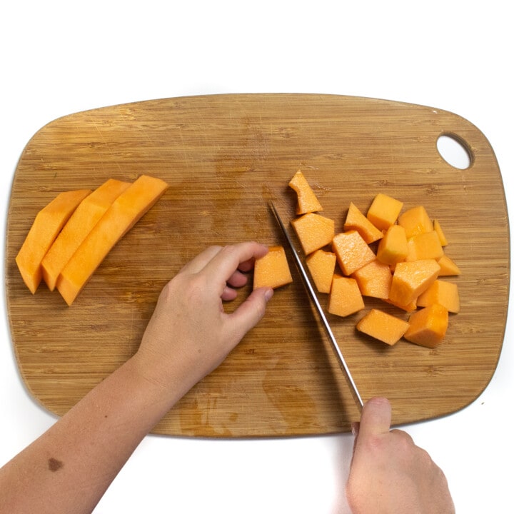 Hans cutting thick slices of cantaloupe into cubes.