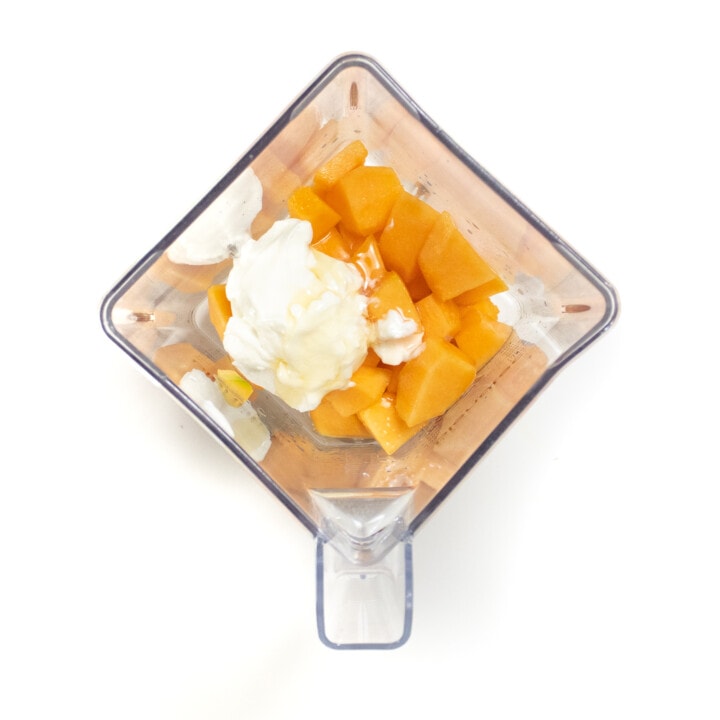 A clear blender with cantaloupe yogurt and lemon juice.