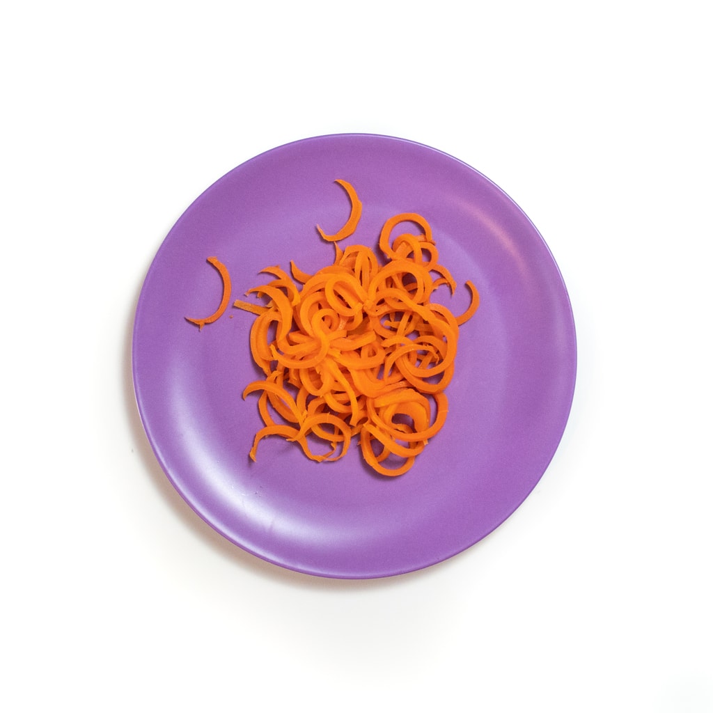 A purple baby plate filled with spiralized carrots.