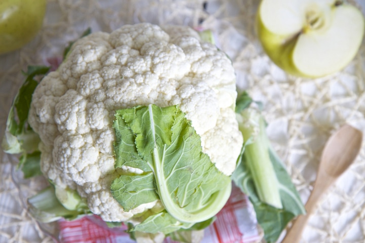 Cauliflower on a white board with napkin underneath it.