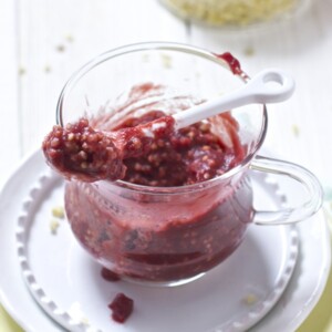 Glass jar filled with carrot, cherry and millet baby food puree.