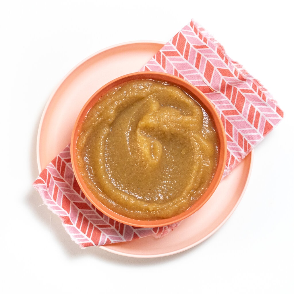 Pink kids bowl with homemade cinnamon applesauce and a pink napkin. 