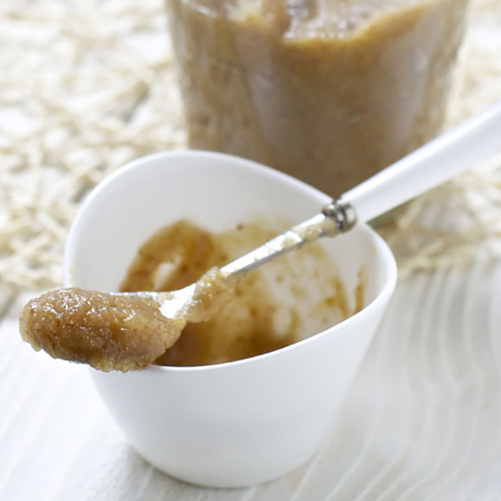 Small bowl filled with baby food puree with spoon resting on top.