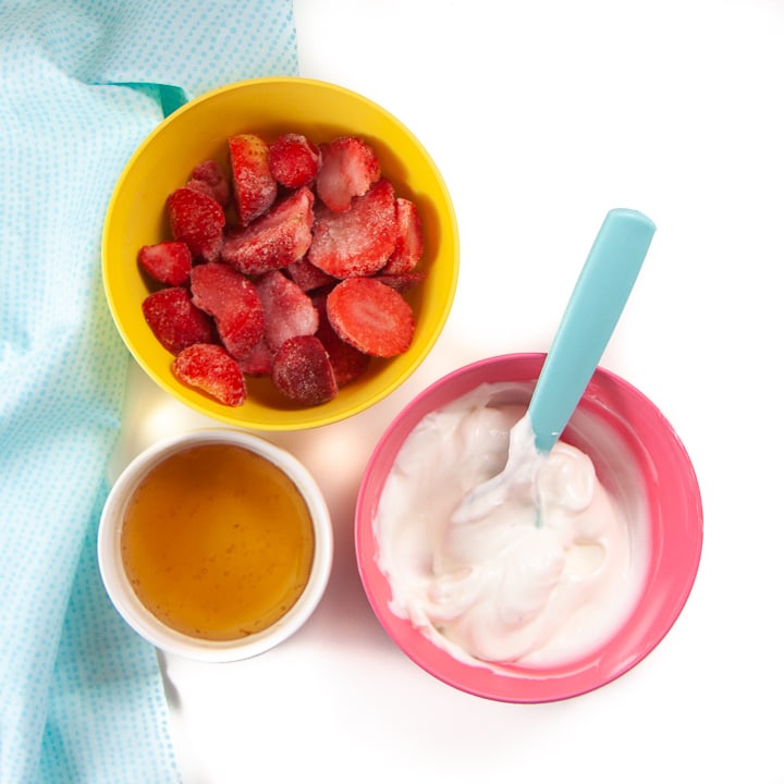 spread of bowls filled with ingredients for yogurt popsicles