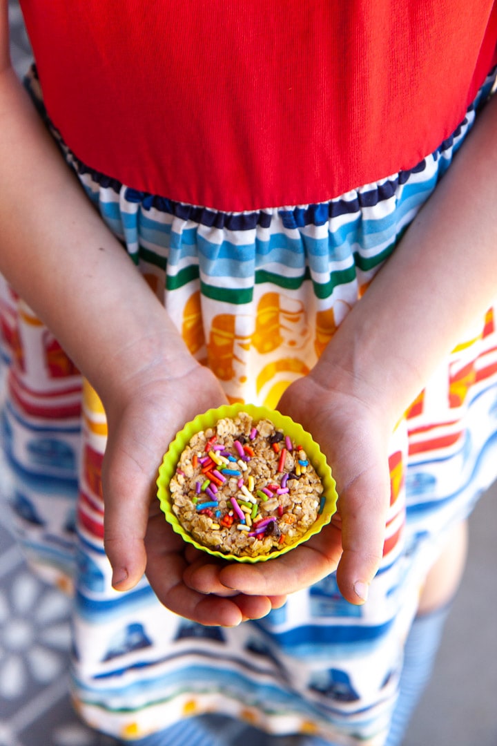 Girl holding a funfetti granola cup in a colorful dress