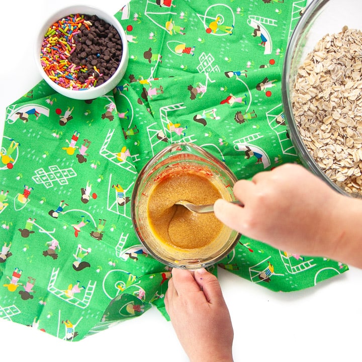 Kid mixing together liquid ingredients for granola bars