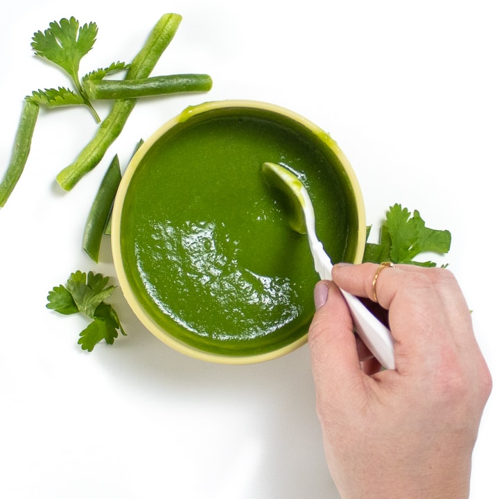 Hand stirring a green bean puree for baby.