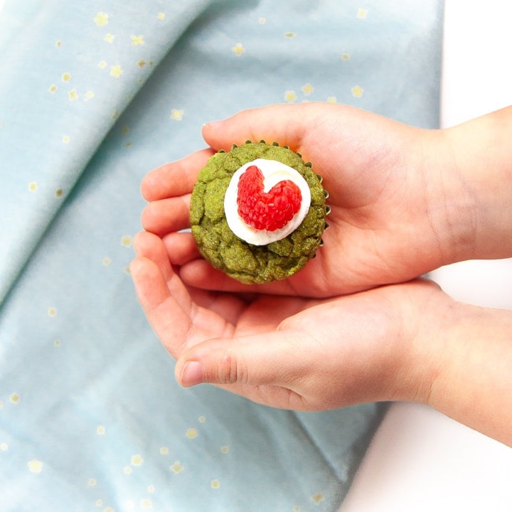 Small hands holding a green muffin.