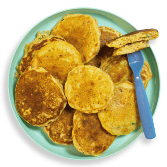 A plate full of veggie pancakes with a fork holding one cut and half on my kitchen counter.