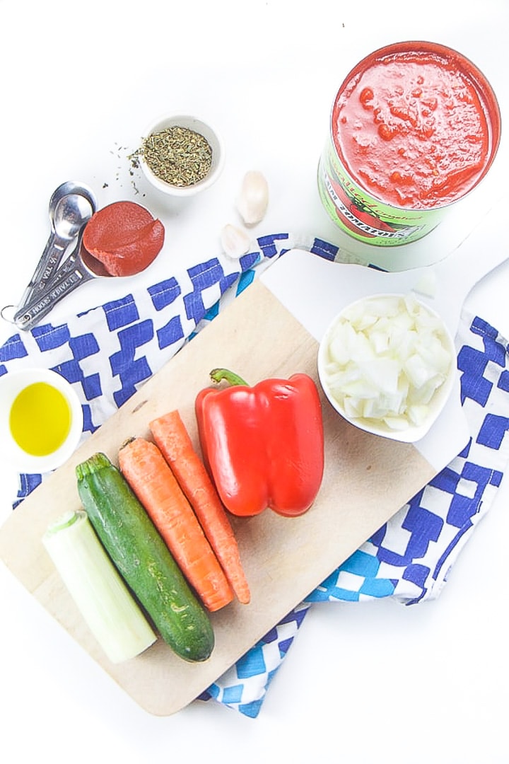 Ingredients for hidden veggie pasta sauce spread out over a cutting board.