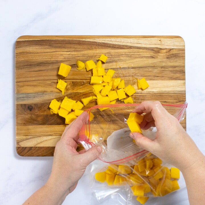 Hands putting mango chunks into a bag.