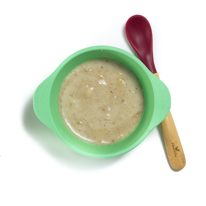 green baby bowl filled with oatmeal puree.