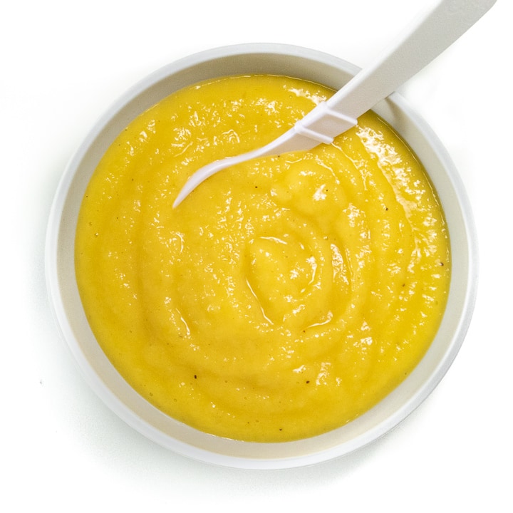 Bowl of homemade baby food puree with mangos, bananas and nutmeg. 