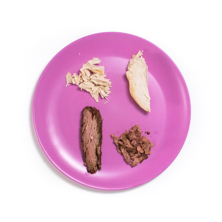 Pink baby plate with chunks and shredded chicken and beef.