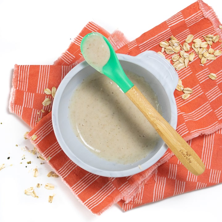 Gray baby bowl filled with pureed oatmeal cereal.