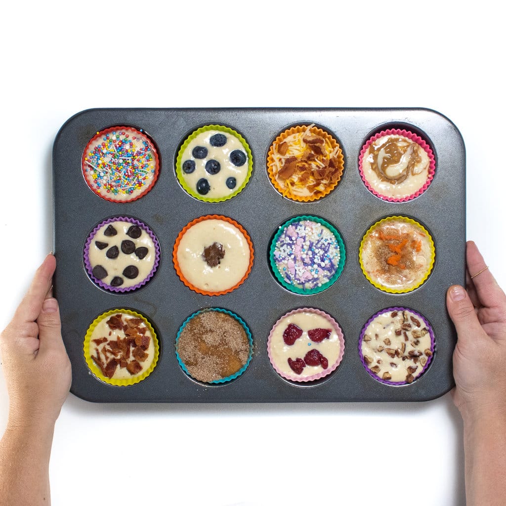 Two hands holding a muffin tin with pancake muffins ready to be baked.