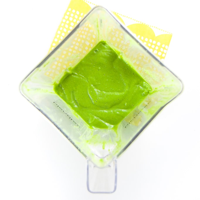 A clear blender filled with a smooth green baby food puree. 