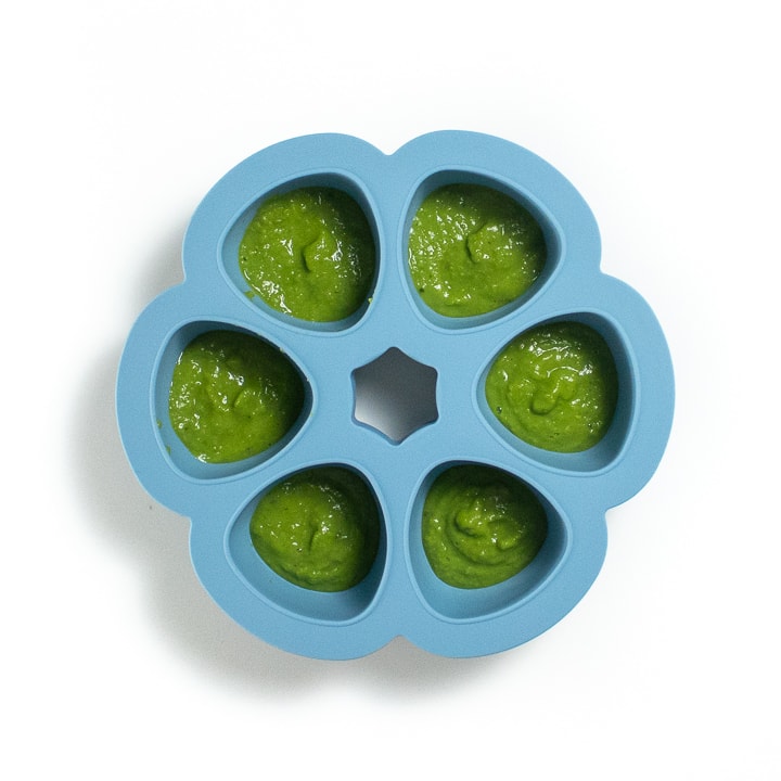 A blue freezer tray with pea puree inside. 