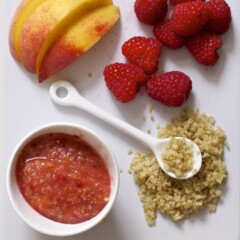 White cutting board with a spread of produce and a small bowl filled with a chunky baby food puree.