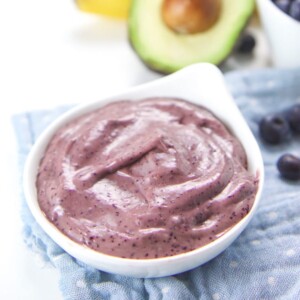 Small white bowl filled with blueberry banana avocado baby food puree.